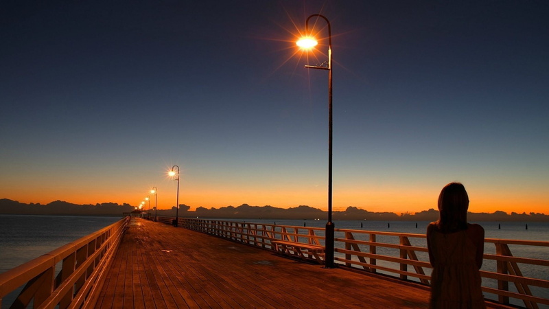 outdoors, railing, street, metal, post, sunset, lighting equipment, 1080P, sea, orange color, street light, water, one person, gray, pier, illuminated