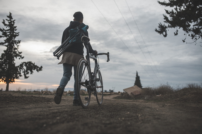 walking, bicycle, person, land vehicle, people, beside, conifer, riding, pine, flora, male, plant, sports, fir, abies, sky, transportation, road, leisure activity