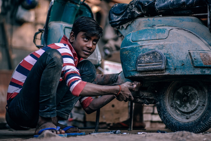 motorcycle, focus on foreground, young adult, motor vehicle, tools, mode of transportation, man, adult, machine, scooter, greasy, vehicle, repairing, mechanic