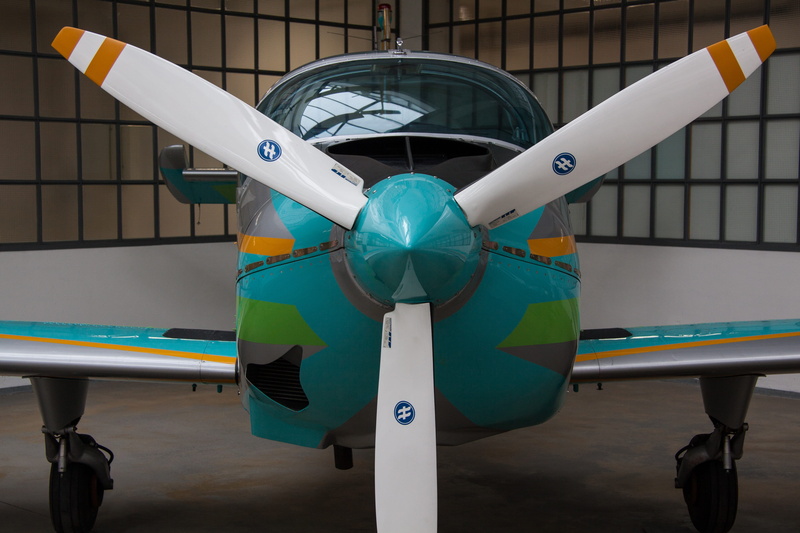 parked, all metal construction, teal, air vehicle, military, trainer aircraft, airplane, mode of transportation, test aircraft, room, multi colored, propeller