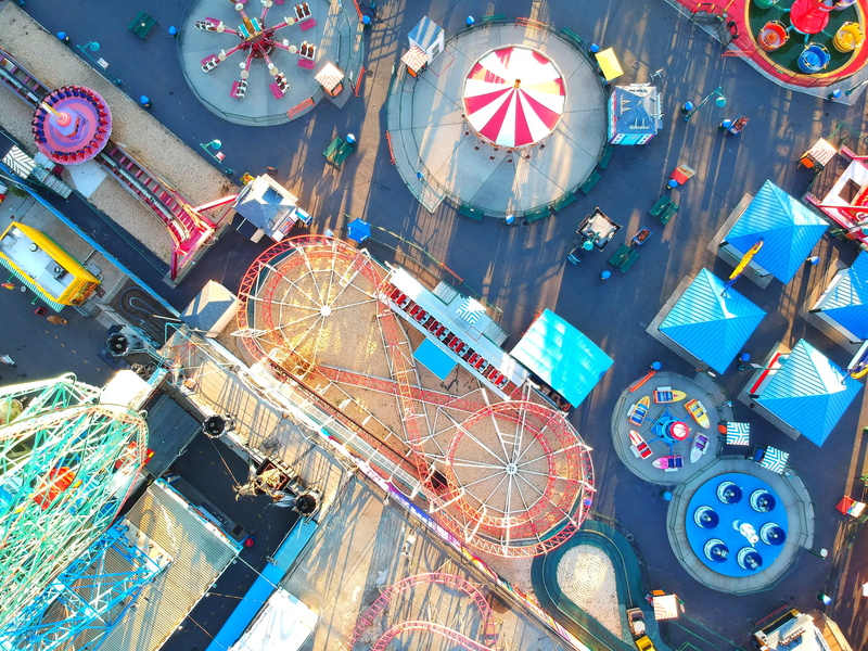 rollercoaster, building exterior, aerial, built structure, park, lighting equipment, city, outdoors, drone, boat, amusement park ride, top, no people, architecture