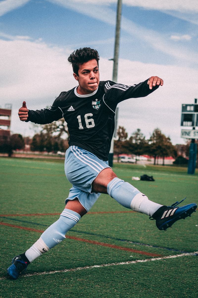 front view, athlete, boy, motion, kicking, sports clothing, black, one person, soccer, clothing, football, jersey, young adult, lifestyles, child, young men