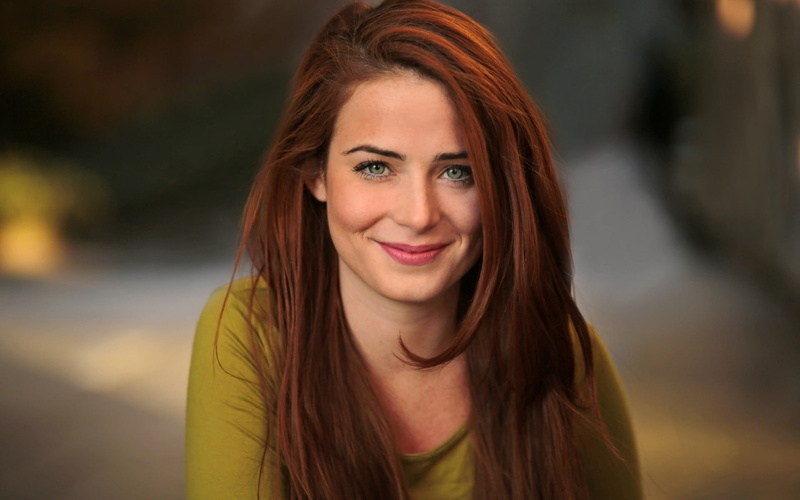 looking at camera, dyed red hair, young adult, emotion, beautiful woman, headshot, focus on foreground, straight hair, cheerful, green eyes, happiness