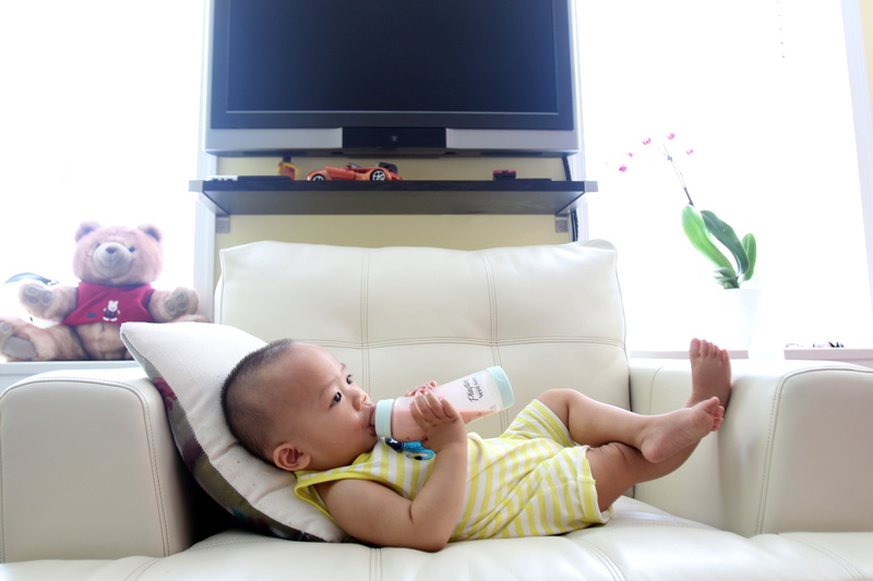 drinking milk, wearing, dairy, legs crossed, one person, little, kid, toy, drinking, feeding, home, onesie, domestic room, infant, care, baby, nutrition