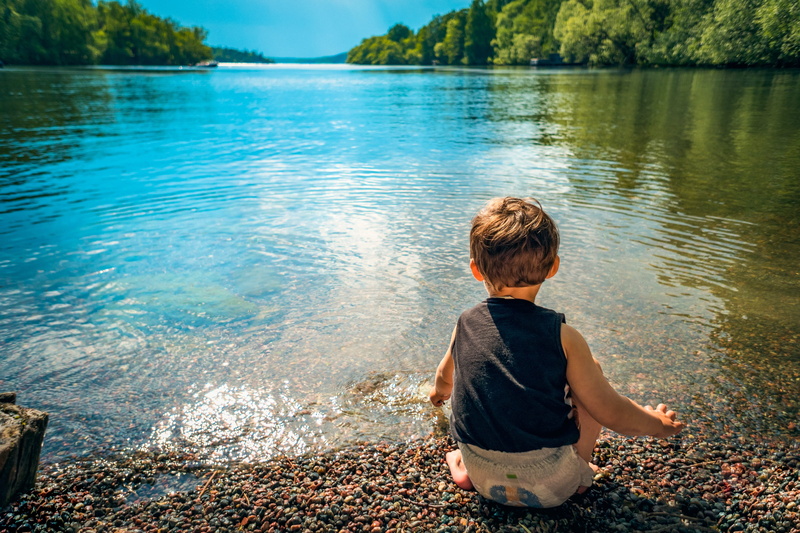 sea, reflection, nature, boys, environment, rays, sitting, sunlight, sunshine, cute, rock, one person, casual clothing, pebbles, child, men, liquid, bottom