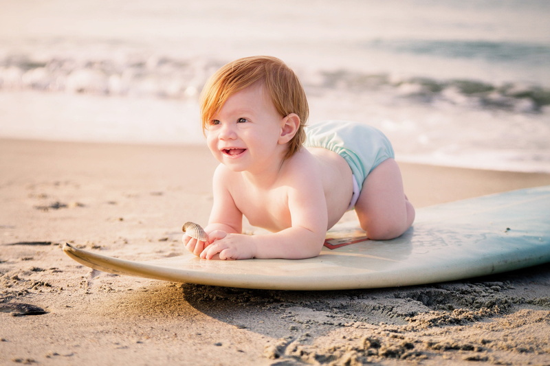 summer, one person, babies only, daytime, childhood, smiling, portrait, brown, riding, surfboard, happy, surfing, seashore, emotion, land, young, sea, water
