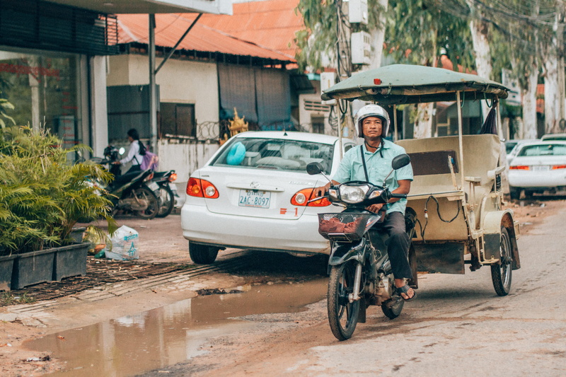 moped, men, vehicle, flora, person, motorcycle, road, bicycle, car, motor scooter, day, mature men, motor vehicle, street, looking at camera, built structure