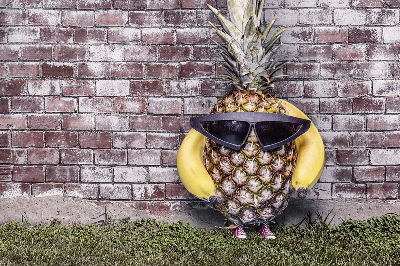 yellow, outdoors, wall - building feature, glasses, sunglasses, silly, fruit, plant part, lazy, architecture, decoration, wearing, brick wall, plant, no people