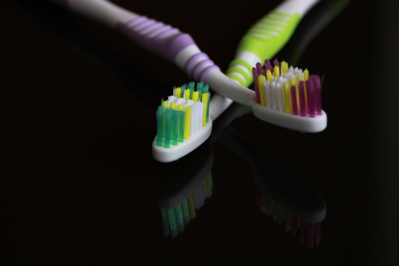 black, oral, food, black background, 4K, close-up, two objects, health, toothbrush, human hand, cupcake, studio shot, human body part, body care, one person