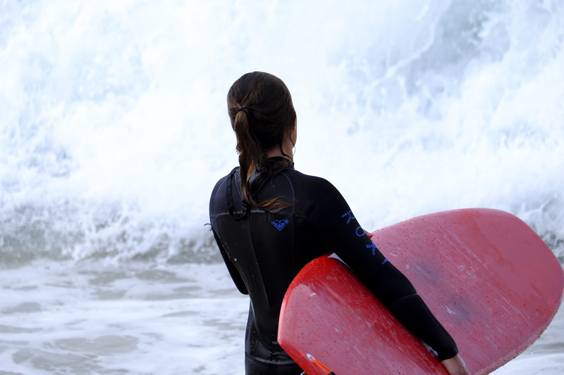 women, beauty in nature, nature, outdoors, real people, wave, fitness, motion, risk, three quarter length, sitting, surfing, one person, strong, performance