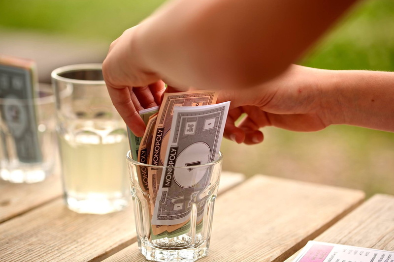 human Hand, cup, offspring, drinking glass, game, wealth, food and drink, dollar, monopoly, finance, human limb, one person, mug, table, refreshment, hand