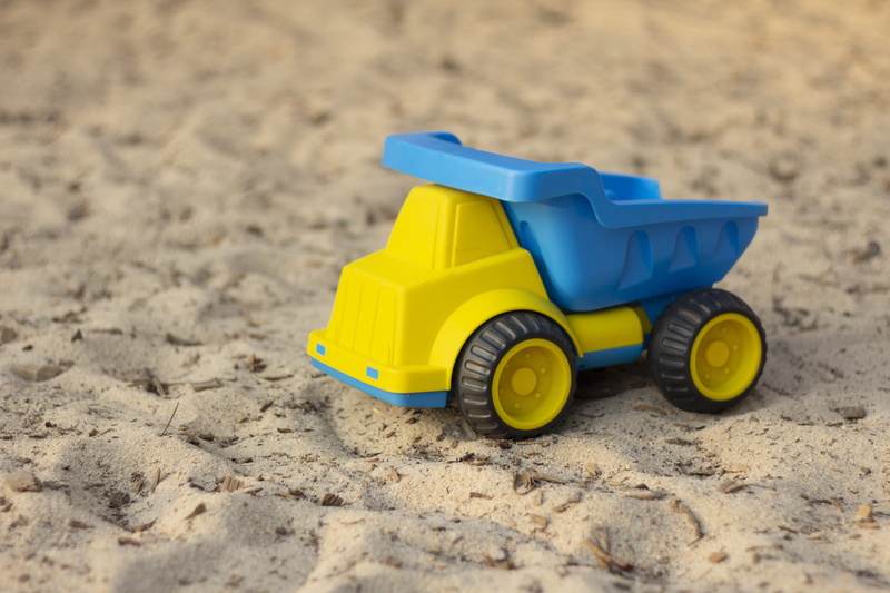toy car, transport, sand pail and shovel, land, still life, car, mode of transportation, beach, sand, nature, park, vehicle, yellow, truck, outdoors, games