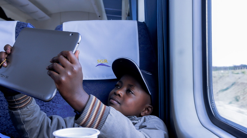 window, childhood, young, youth, males, communication, technology, sitting, skin, mombasa, style, looking, person, indoors, train, happy, public transportation