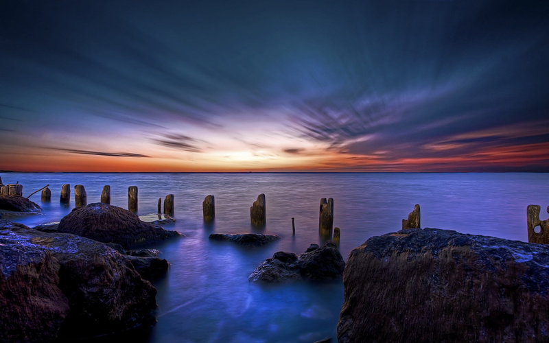 wooden, groyne, cloud - sky, coast, tranquil scene, horizon over water, brown, posts, rock, tranquility, dramatic sky, beach, land, sunset, solid, purple