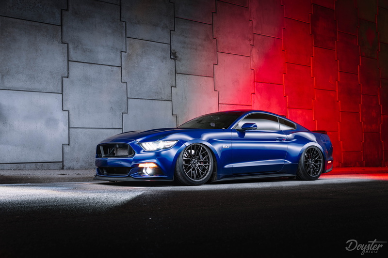 outdoors, transportation, mode of transportation, blue, street, city, car, sports car, garage, wall, land vehicle, wealth, red, luxury, built structure
