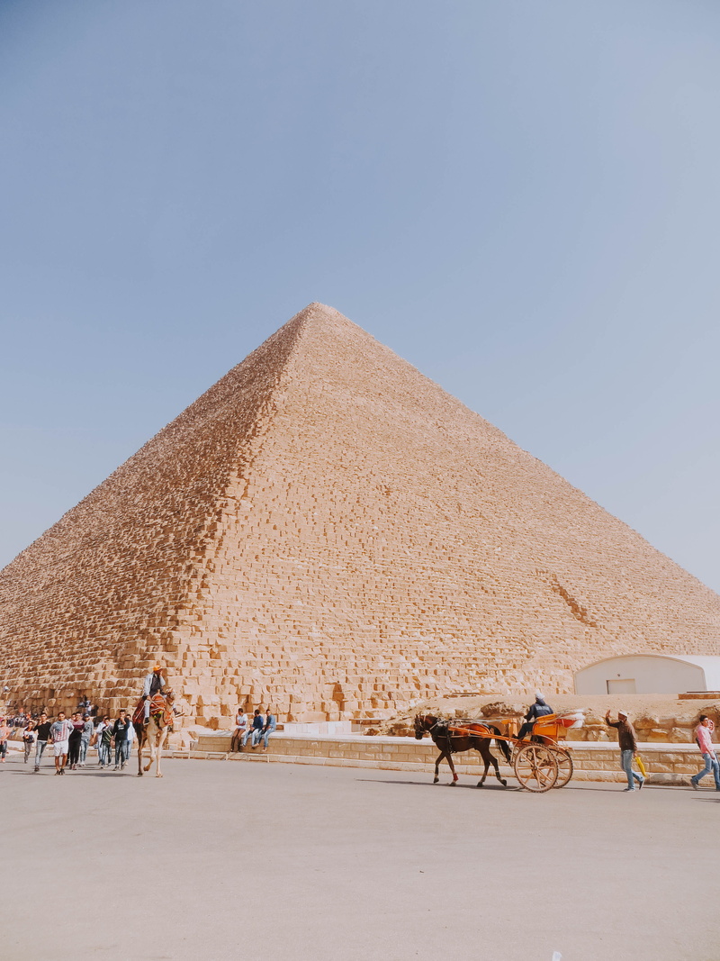 sky, pyramid, town, travel, architecture, livestock, horse, neighborhood, triangle, egypt, metropolis, ride, desert, vehicle, city, ruins, camel, human