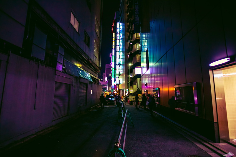 building exterior, road, city, direction, real people, walking, urban, dark, night, cityscape, group of people, neon lights, architecture, illuminated