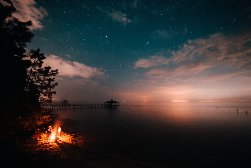 person, land, astrophotography, campfire, nature, lake, night, beauty in nature, bonfire, star - space, ocean, tranquil scene, reflection, body, tranquility