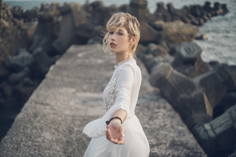 model, dress, rocks, sea, women outdoors, women, looking at viewer, blonde, hair in face, short hair, depth of field, 1080P