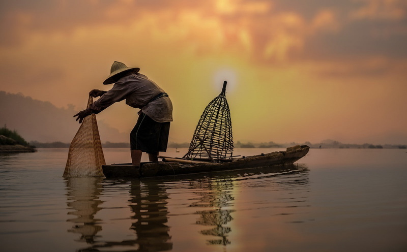 nautical vessel, orange color, one person, hat, sunlight, transportation, beauty in nature, nature, fishing net, sunset, fishing, waterfront, occupation
