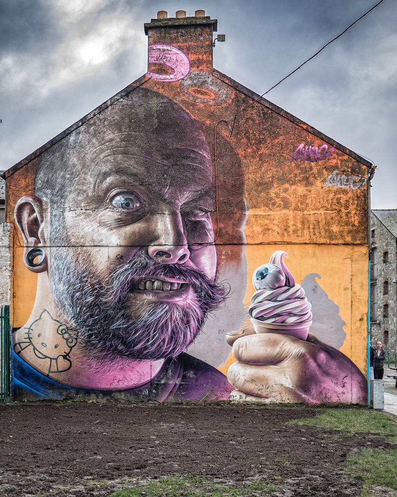 wall, building exterior, cloud - sky, cream, built structure, representation, cumulus, male likeness, art, icecream, holding, printed, multi colored, mural