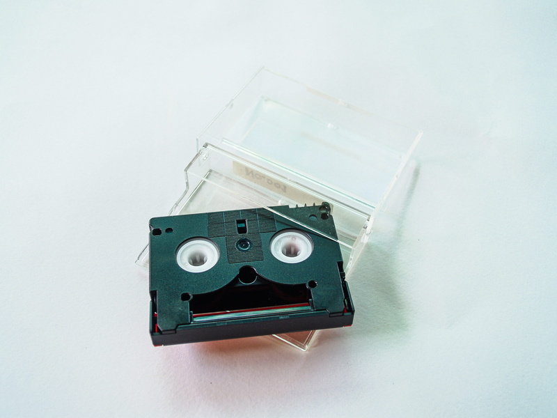 music, 2K, white background, portable, camera - photographic equipment, close-up, single object, cassette tape, electrical equipment, power supply, indoors