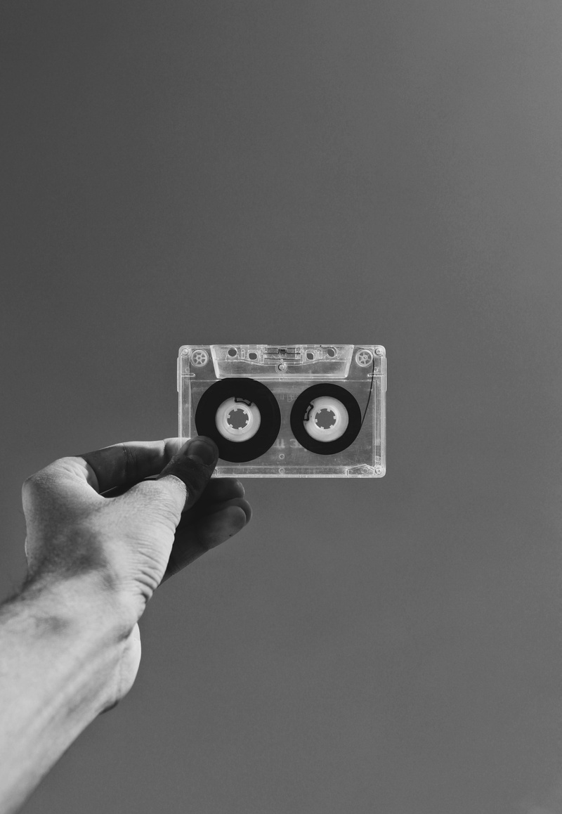 cassette tape, finger, gray background, indoors, cassette, communication, person, copy space, body part, wall - building feature, human limb, retro, monochrome