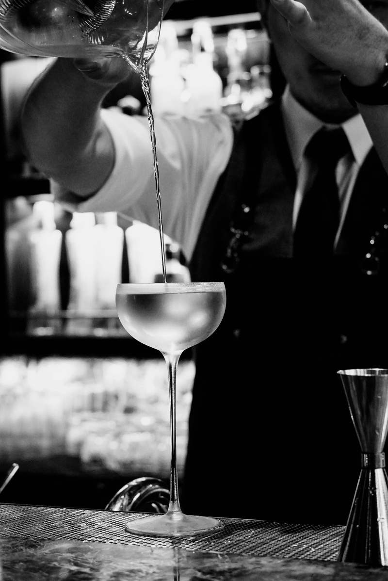 indoors, black, worker, martini glass, food and drink, waiter, shelf, goblet, bar counter, human, preparation, drink, focus on foreground, midsection, pub