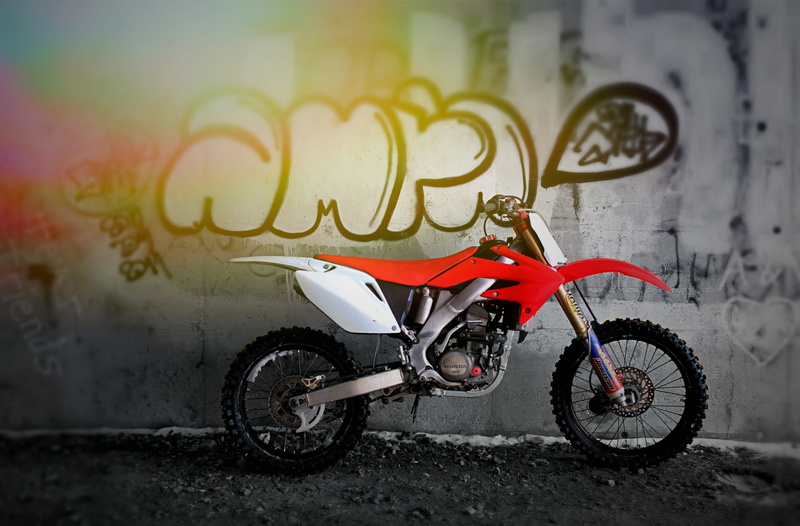stationary, sport, outdoors, street, bike, city, day, graffiti, communication, white, wall - building feature, land vehicle, dirtbike, red, motocross, dirt