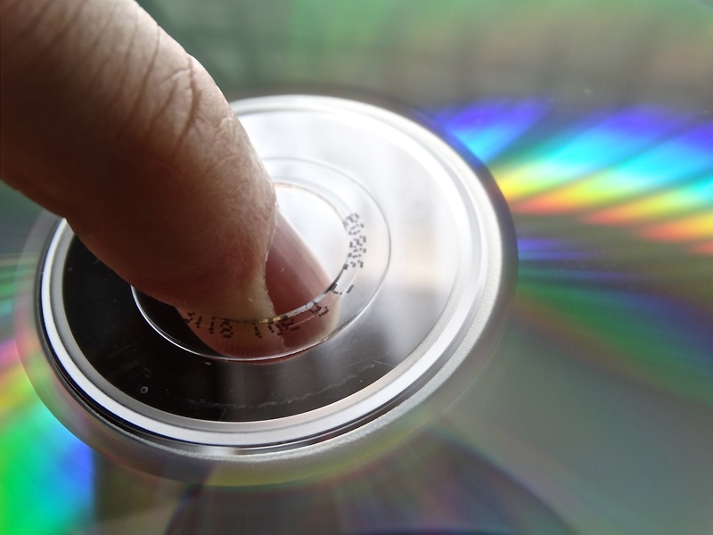 human hand, lift, indoors, technology, western script, data, color, focus on foreground, lifestyles, human body part, dVD, floppy disk, shape, body part