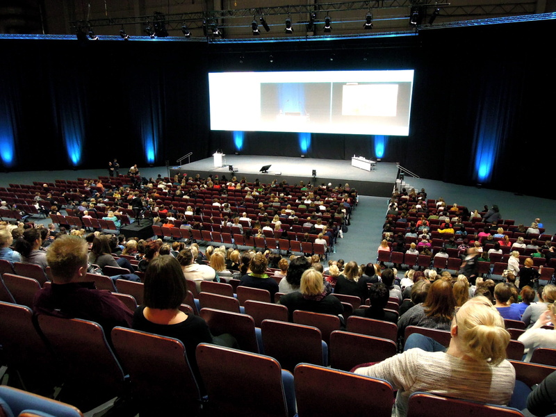 stage - performance space, watching, projection screen, crowd, lecture, spectator, large group of people, real people, indoors, rear view, high angle view