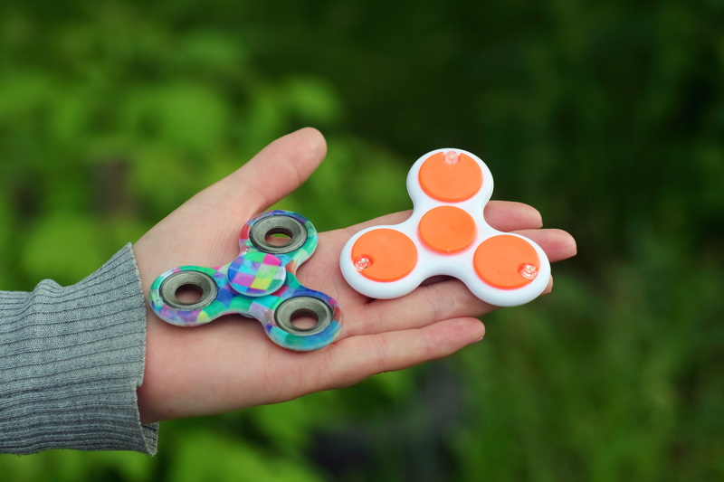 counter, figet spinner, human hand, day, leisure activity, spinner, popular, body part, holding, unrecognizable person, real people, play, human limb, toy trend