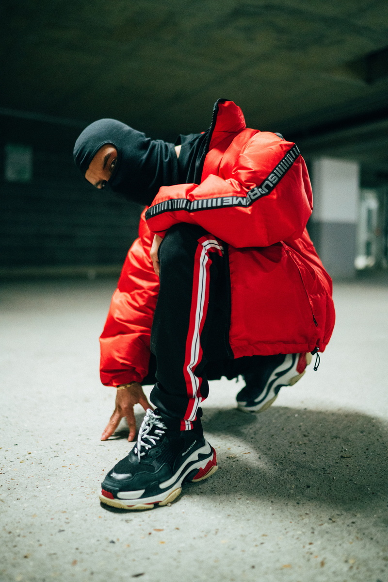 sitting, floor, clothing, women, real people, outdoors, street style, kneeling, looking, one person, leisure activity, balaclava, shoe, full length, dancing