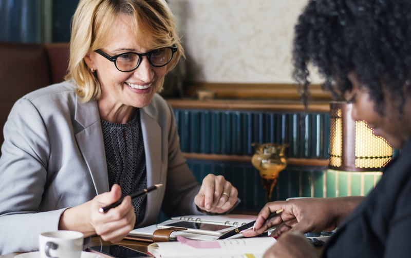 eyeglasses, businesswomen, mature women, women, table, glasses, female, education, smiling, adults, writing, two, two people, work, discussing, discussion