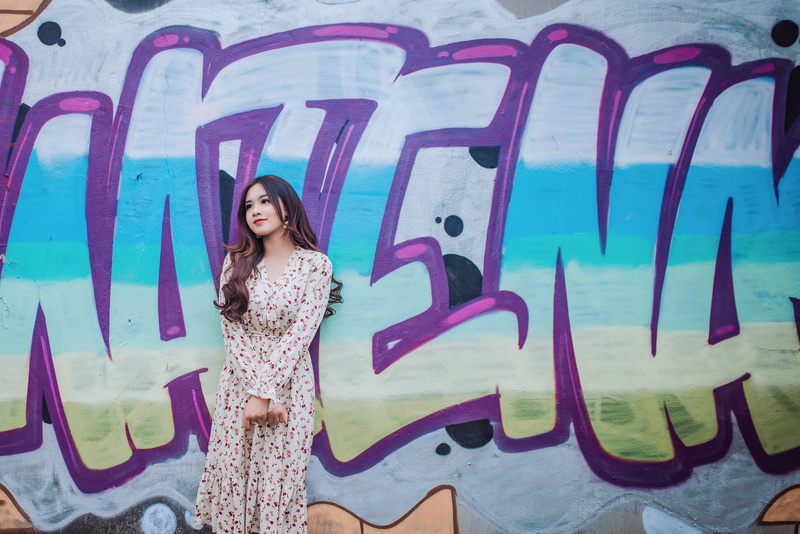 casual clothing, street, lips, looking at camera, young adult, street art, woman, creativity, wall, standing, hairstyle, spray paint, smiling, hair, leisure activity