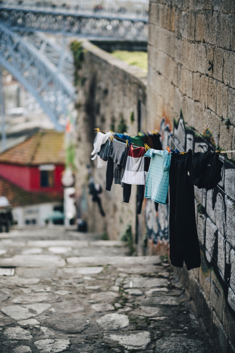 residential district, wall - building feature, no people, building, sidewalk, walkway, road, pavement, hanged, path, clothesline, undershirt, focus on foreground