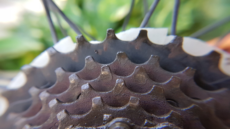 selective focus, serrated, close-up, chain, gears, small group of objects, cogwheel, machinery, outdoors, mode of transportation, steel, extreme close-up