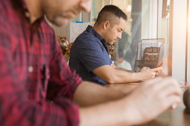 phone, looking down, adult, black, modern, sales pro, two people, hands, working, sleeved, communication, male, sitting, shirt, selective focus, wearing