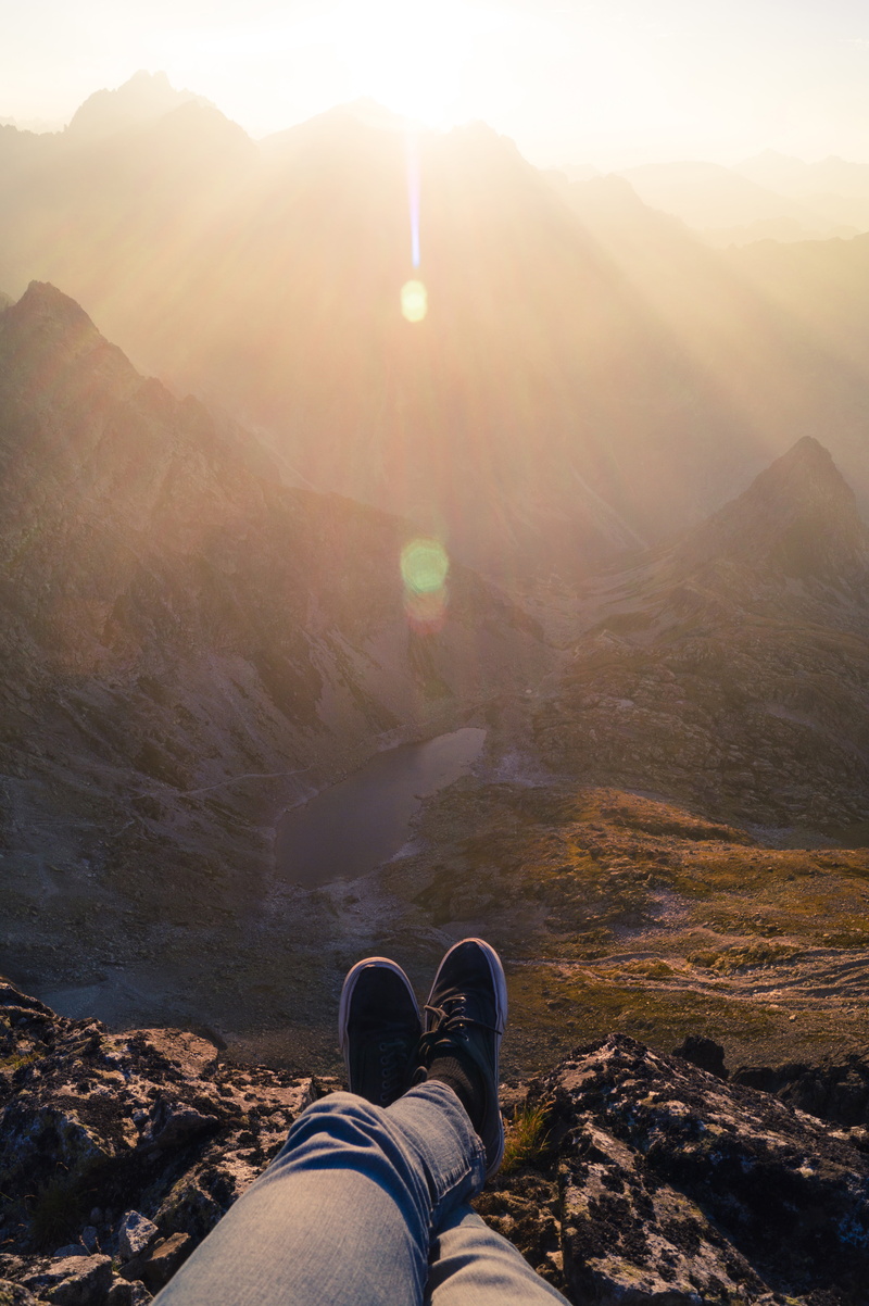 body part, landscape, shoe, personal perspective, black, 5K, human body part, human leg, one person, mountain range, pants, sunrise, mountains, sunbeam