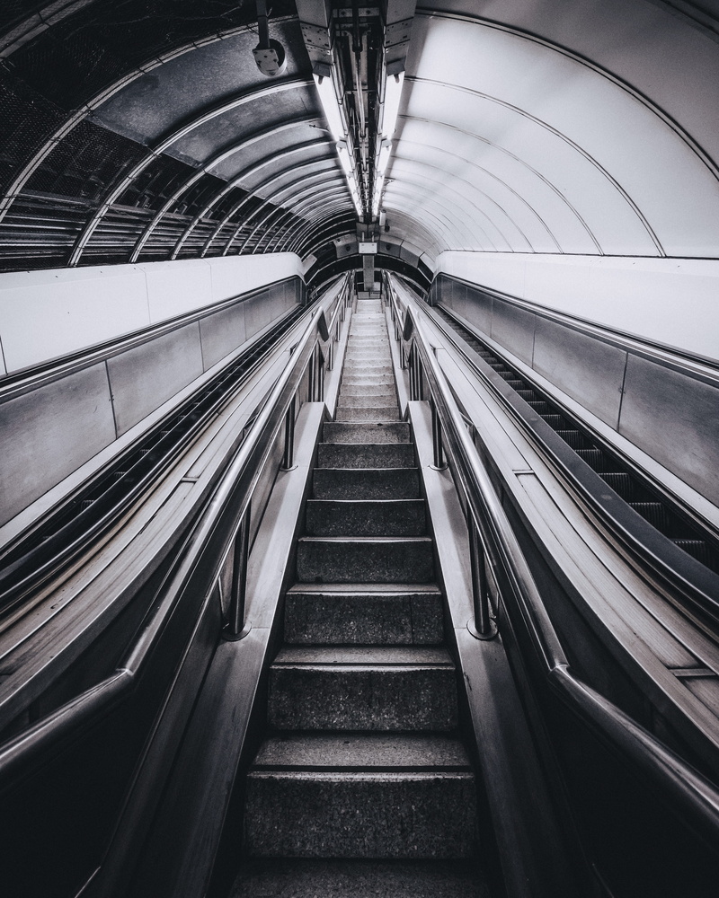 ceiling, subway station, railing, perspective, diminishing perspective, convenience, built structure, underground, looking up, tunnel, staircase, gray