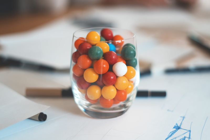 bubbles, sphere, food and drink, paper, food, text, focus on foreground, finger, candy, table, close-up, fruit, large group of objects, arcade game machine