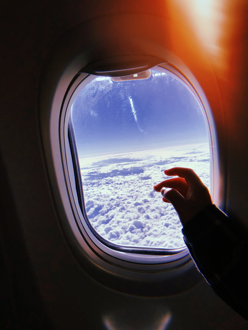 one person, flying, travel, artsy, human body part, plane window, aesthetic, light, transparent, nature, plane, flare, window, sky, mode of transportation