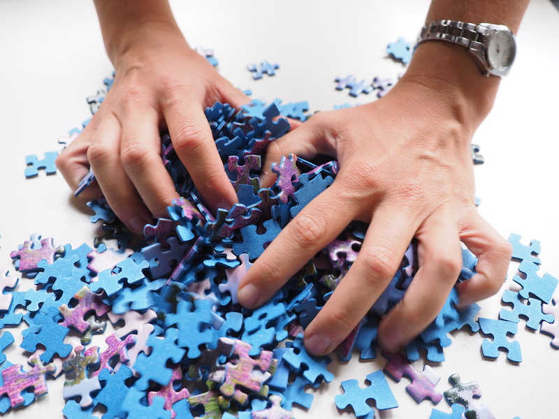 real people, human Hand, pastime, business, patience, one person, close-up, table, solution, memory cards covered with, boredom, pieces, teamwork, purple