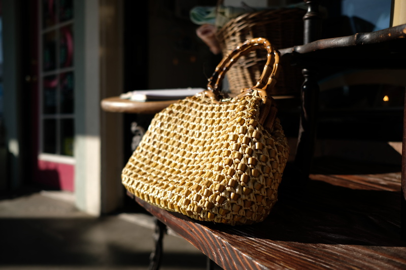 purse, wicker, plastic, plastic bag, clothing, shopping basket, selective focus, metal, tote bag, small business, indoors, shelf, table, still life, accessories
