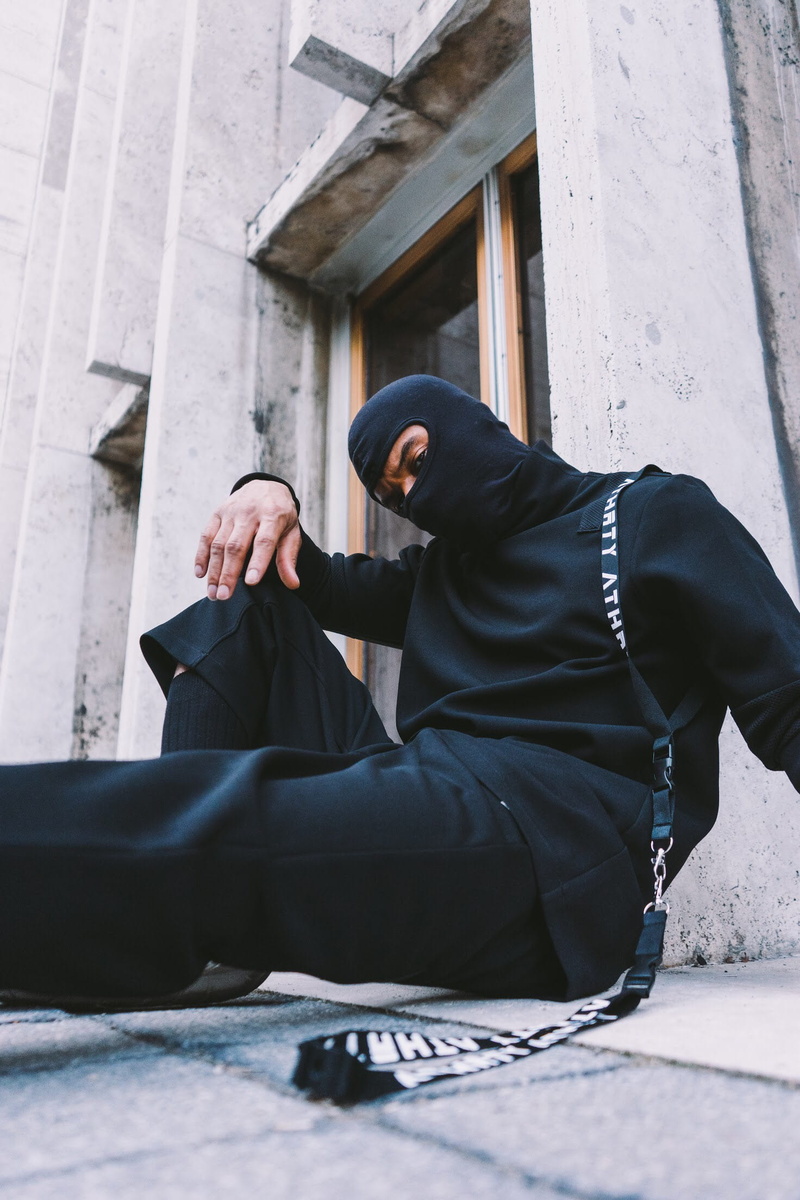 social issues, architecture, built structure, sitting, urban, young adult, clothing, hood - clothing, mask, front view, shoulder, leisure activity, real people
