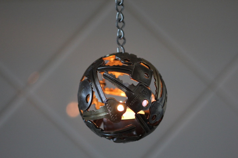DIY, close-up, light, ball, focus on foreground, chain, 720P, depth of field, hanging, metal, artwork, candles, studio shot, no people, gray, wall, lights