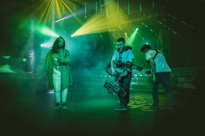 film set, nightlife, standing, adult, array alexa mini, video camera, stage - performance space, musician, slow motion, stage, dance floor, steadicam, illuminated