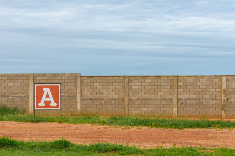 safety, soil, shooting range, sign, outdoors, brown, a, field, text, land, ground, security, sky, plant, gravel, wall, symbol, communication, protection
