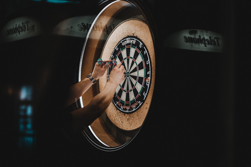 arms raised, darts, western script, time, one person, picking, sport, hands, men, person, clock, light, human body part, dartboard, human arm, text, young men