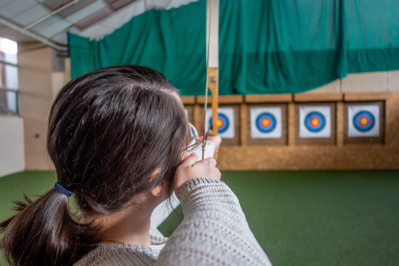 focus on foreground, black hair, person, target, archer, indoors, headshot, architecture, portrait, objective, leisure activity, adult, sport, 5K, child